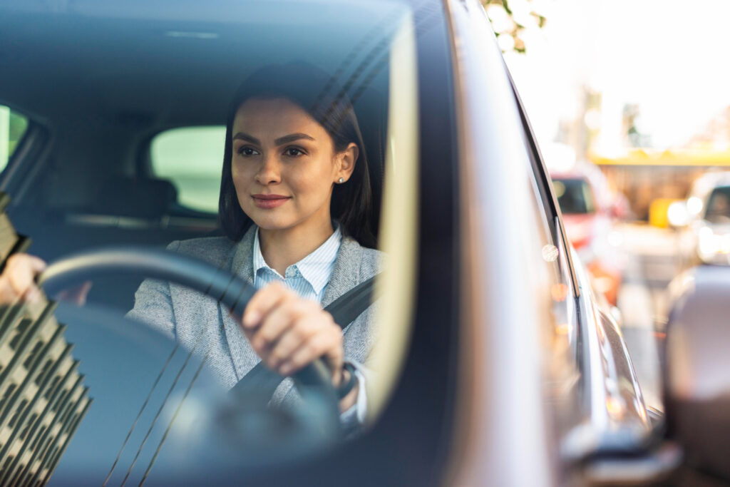 A confident adult female student holding the steering wheel during in-car driving lessons, practicing city driving maneuvers.